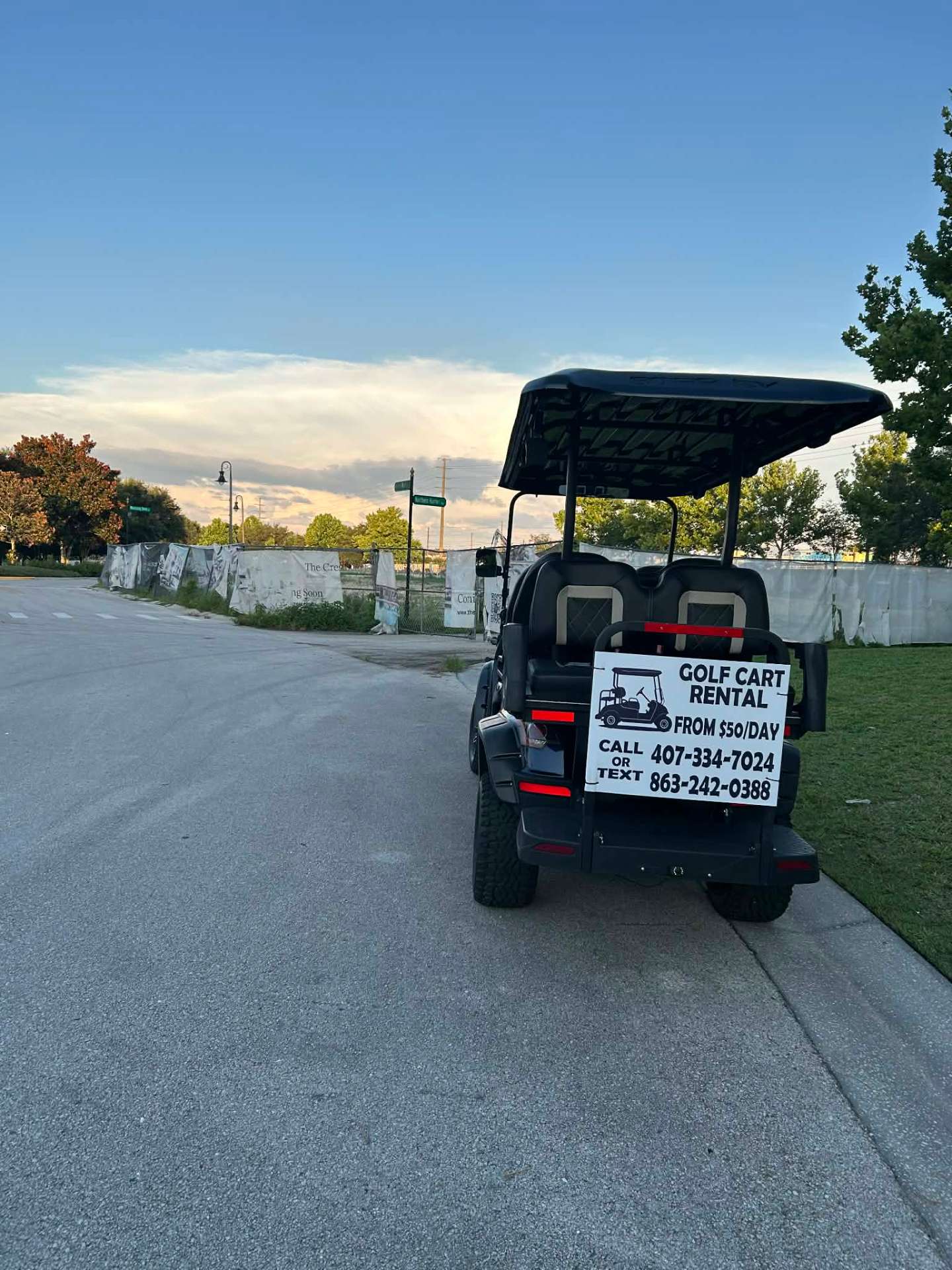 Rear view of black luxury golf cart with Golf Cart Rental $50/day call or text sign at sunset