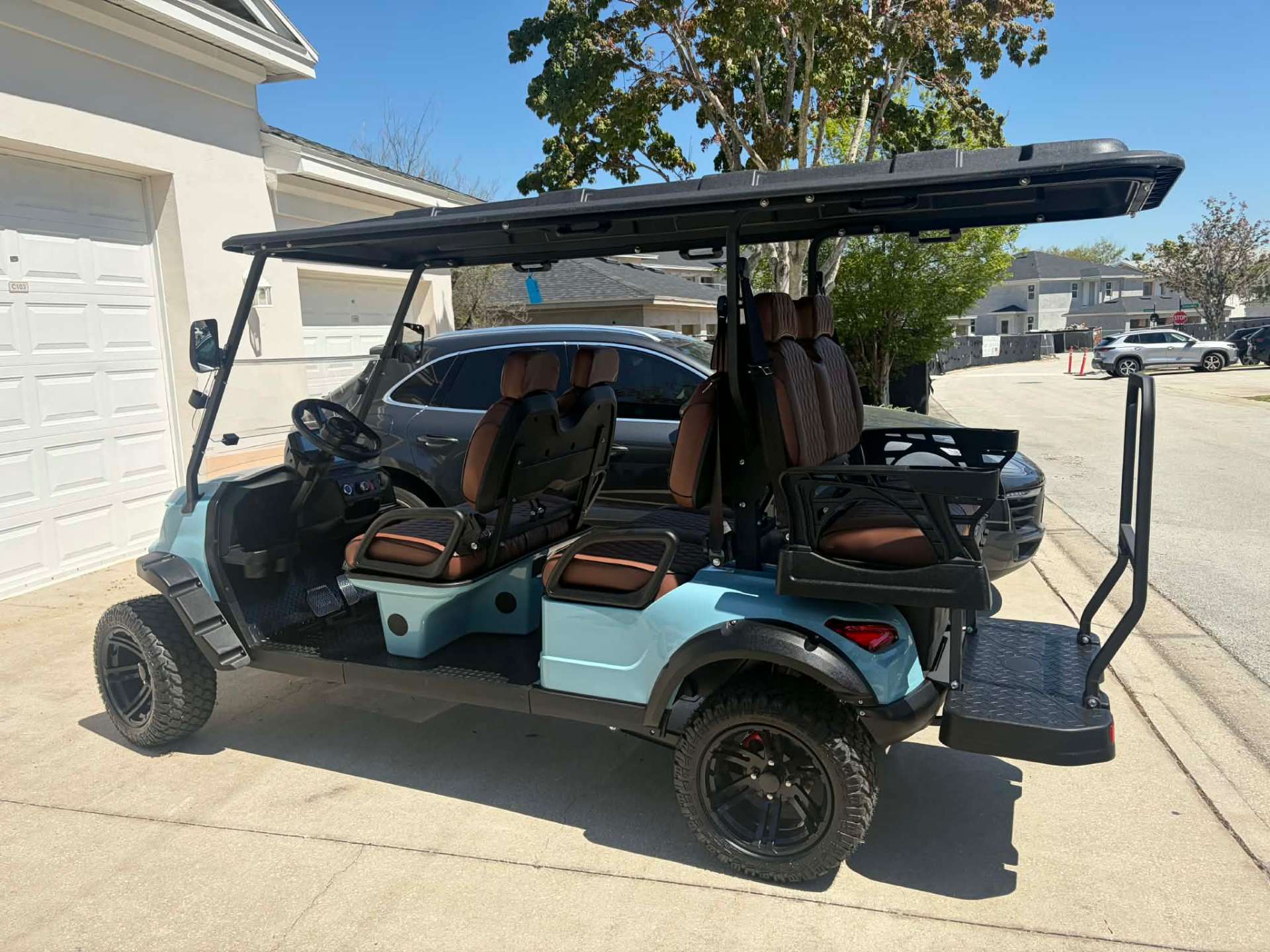 Side view of teal 6-passenger luxury golf cart in a Reunion Resort driveway