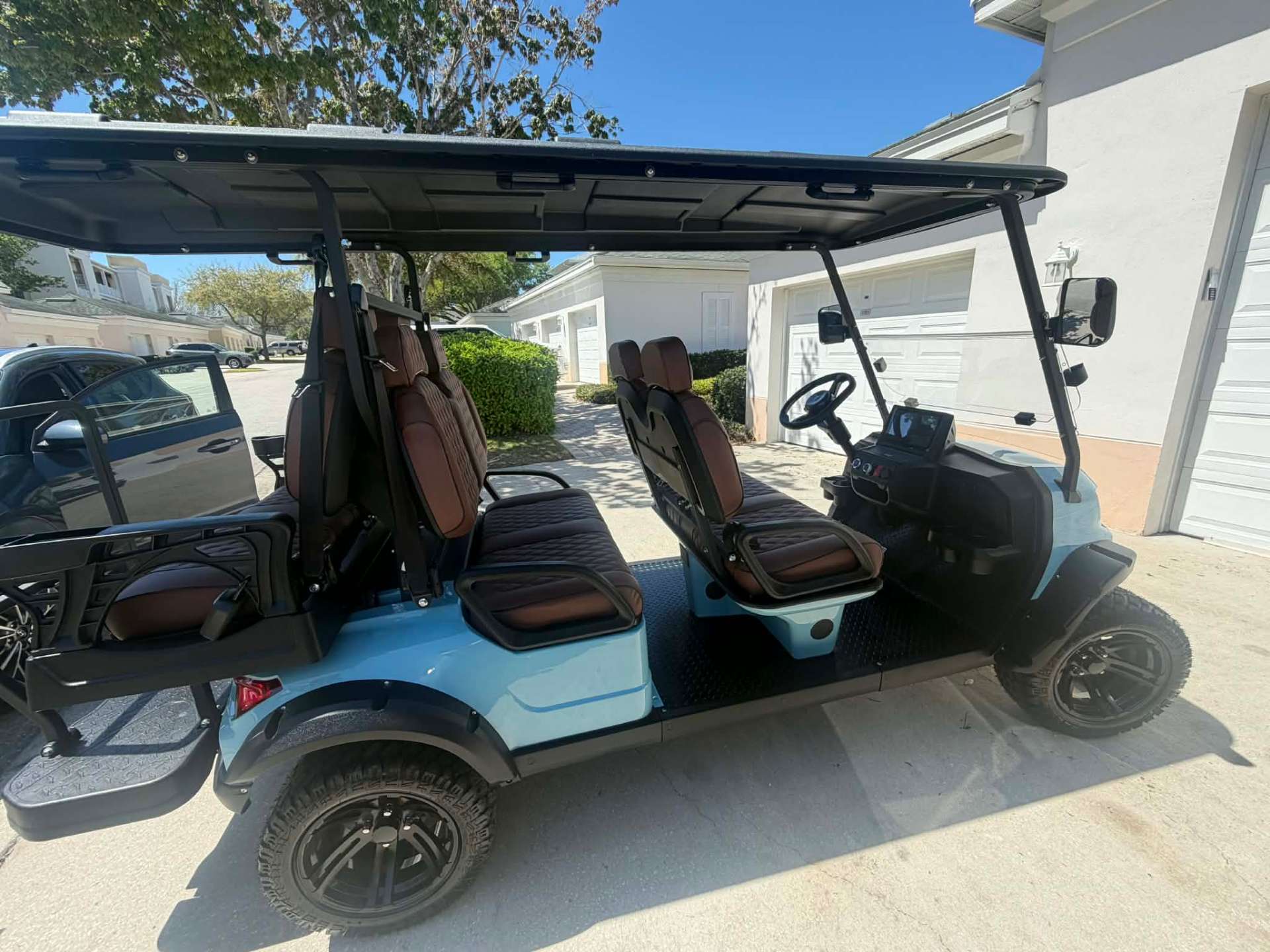 Side profile of teal 6-passenger luxury golf cart in a Central Florida driveway